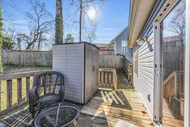 wooden deck featuring a storage shed, a fenced backyard, and an outbuilding