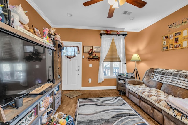 living area featuring baseboards, visible vents, crown molding, and wood finished floors