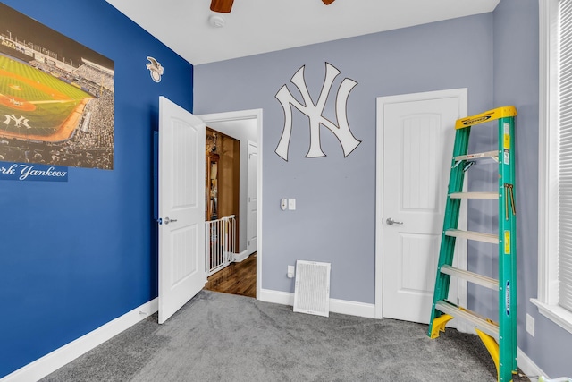 unfurnished bedroom with carpet floors, visible vents, baseboards, and a ceiling fan