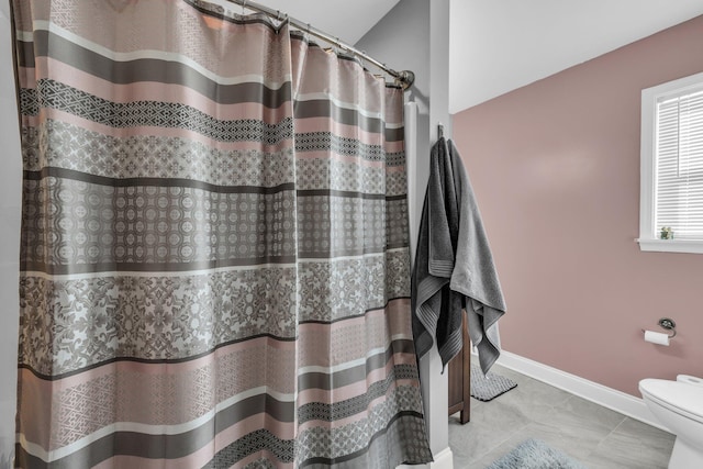 bathroom featuring a shower with shower curtain, baseboards, toilet, and tile patterned floors