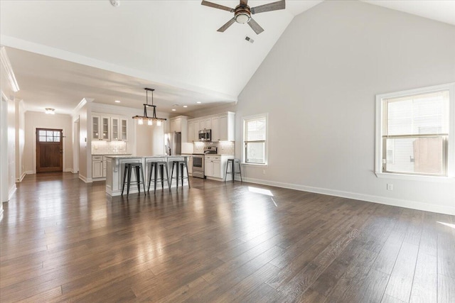 living area with baseboards, a healthy amount of sunlight, dark wood finished floors, and a ceiling fan