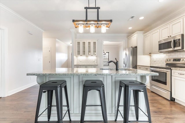 kitchen featuring a kitchen breakfast bar, stainless steel appliances, dark wood-type flooring, and crown molding