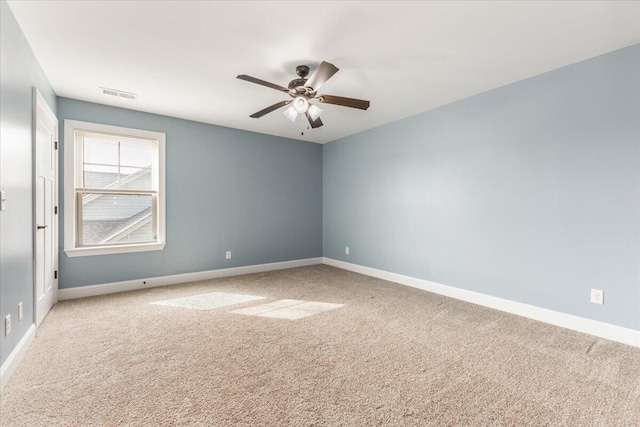 carpeted spare room with visible vents, baseboards, and ceiling fan