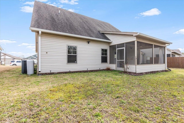 rear view of property featuring a lawn, fence, a sunroom, and roof with shingles