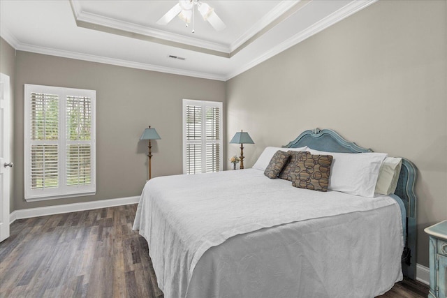 bedroom with a tray ceiling, dark wood-style flooring, and baseboards