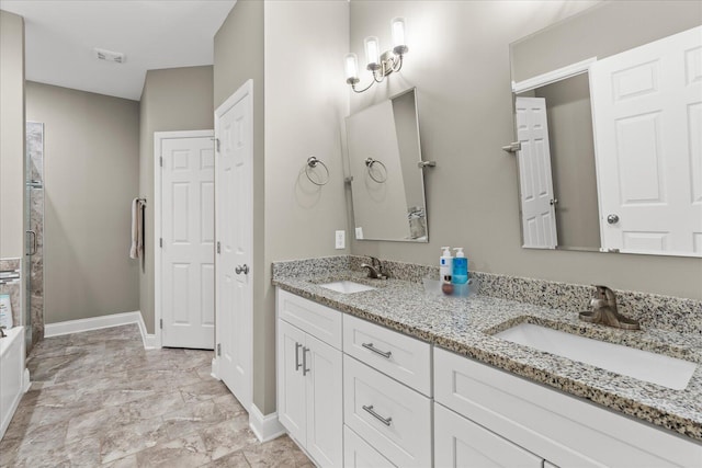 bathroom featuring double vanity, a stall shower, baseboards, and a sink