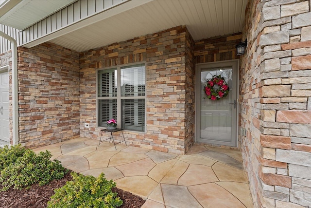 view of exterior entry featuring board and batten siding and brick siding