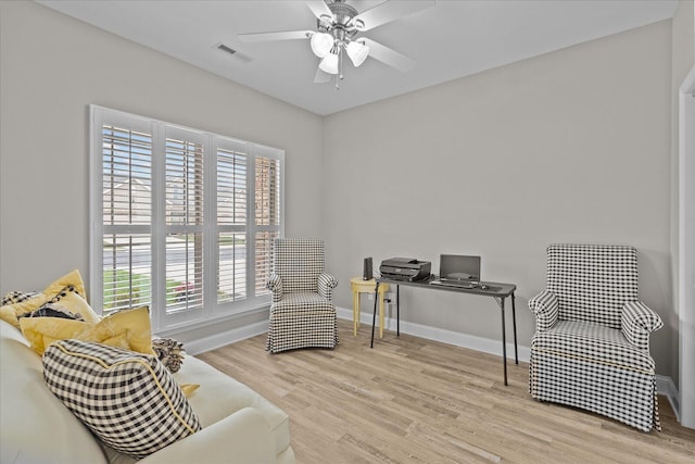 sitting room with ceiling fan, wood finished floors, visible vents, and baseboards