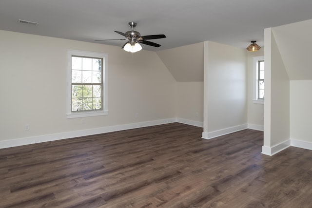 additional living space with visible vents, a ceiling fan, baseboards, dark wood-style flooring, and vaulted ceiling