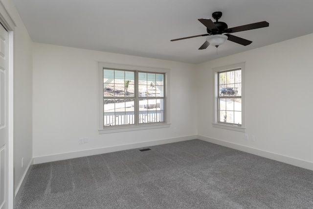 empty room with visible vents, baseboards, ceiling fan, and dark carpet