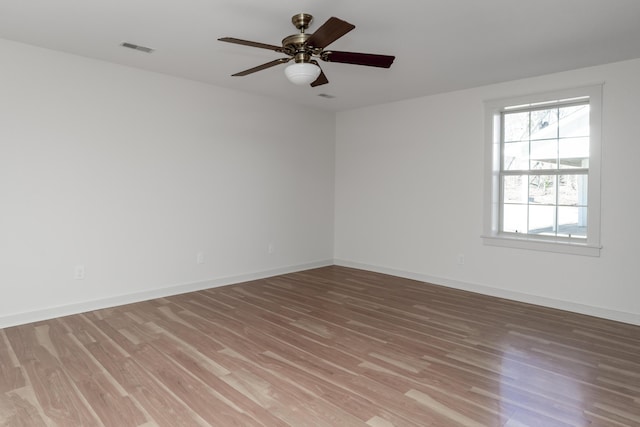 unfurnished room featuring baseboards, visible vents, light wood finished floors, and ceiling fan