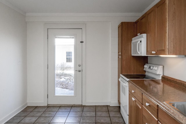 kitchen with white appliances, baseboards, light tile patterned flooring, a sink, and brown cabinets