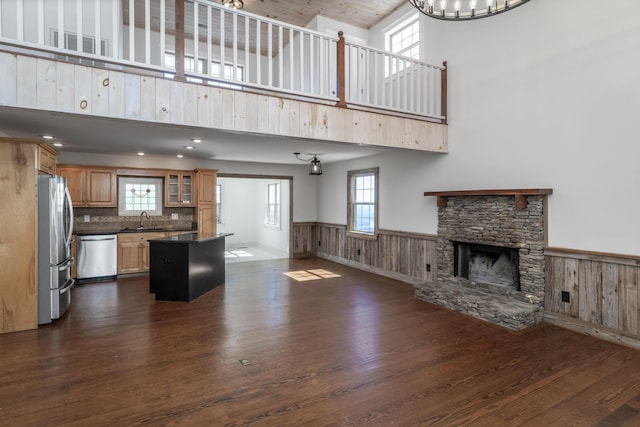 unfurnished living room with visible vents, dark wood-type flooring, a sink, a fireplace, and wainscoting