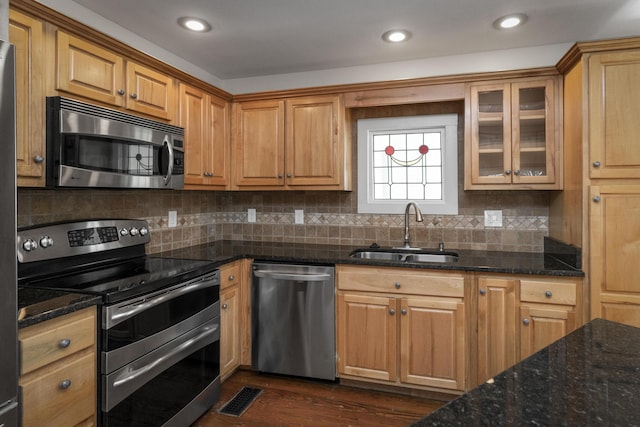 kitchen featuring visible vents, a sink, dark stone countertops, tasteful backsplash, and appliances with stainless steel finishes