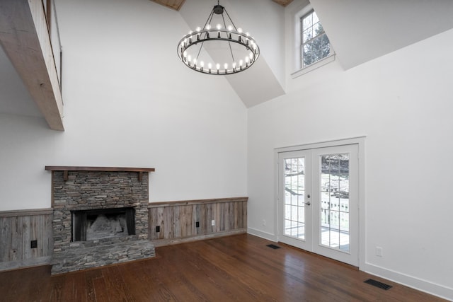 unfurnished living room with wood finished floors, visible vents, a high ceiling, french doors, and a notable chandelier