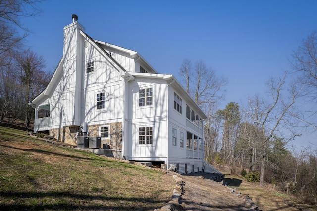 view of side of property featuring central AC unit, a chimney, and a yard