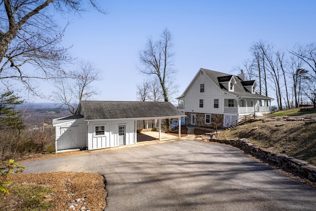 view of front of house with an attached carport, aphalt driveway, board and batten siding, and covered porch