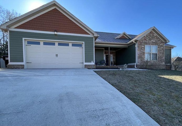 view of front of house featuring a garage, stone siding, and driveway