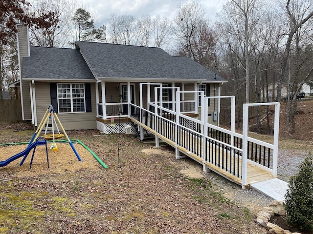 view of front facade featuring a shingled roof, a chimney, and a playground