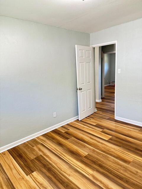 unfurnished room with baseboards and wood finished floors