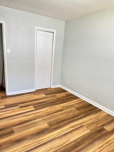 unfurnished bedroom with a closet, baseboards, and wood finished floors