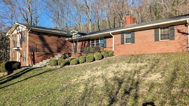 view of front of property with brick siding, a chimney, a front lawn, and stairway