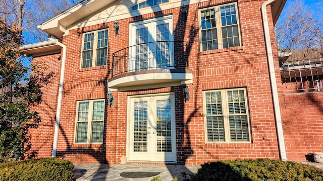 view of exterior entry featuring a balcony and french doors