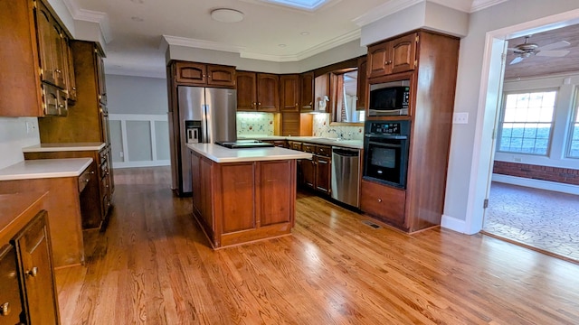 kitchen with light wood finished floors, stainless steel appliances, ornamental molding, and a kitchen island