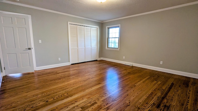 unfurnished bedroom featuring dark wood-style floors, ornamental molding, and visible vents