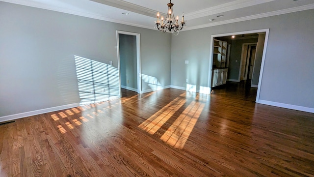 empty room with baseboards, ornamental molding, wood finished floors, and an inviting chandelier