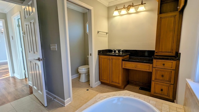 bathroom featuring tile patterned floors, toilet, ornamental molding, a sink, and a bath