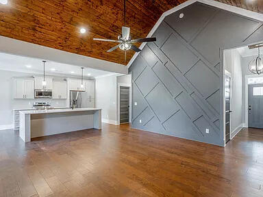 unfurnished living room featuring dark wood-style floors, wood ceiling, baseboards, and ceiling fan with notable chandelier