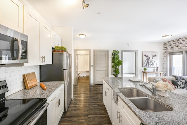 kitchen with dark wood finished floors, a sink, stainless steel appliances, white cabinets, and backsplash