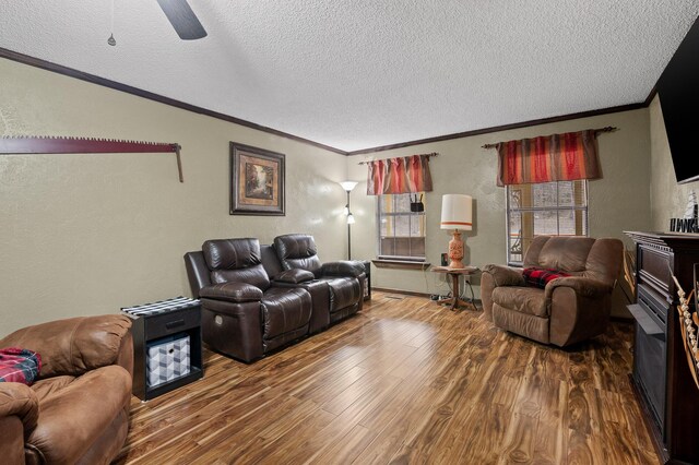 living room featuring a textured ceiling, a textured wall, wood finished floors, and crown molding