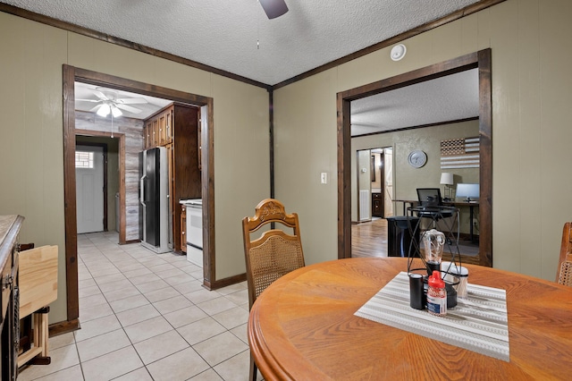 dining space with a textured ceiling, ornamental molding, light tile patterned floors, and a ceiling fan