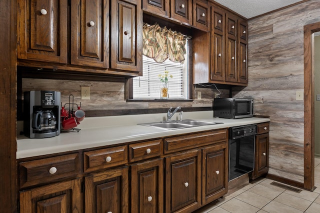 kitchen with light tile patterned flooring, wall oven, a sink, visible vents, and light countertops