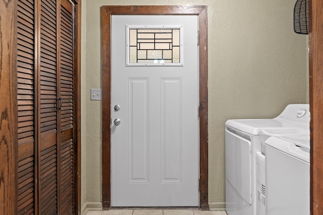 washroom with washing machine and dryer, laundry area, light tile patterned flooring, and a textured wall