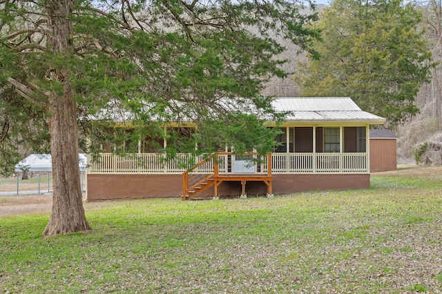 rear view of house with a sunroom, a lawn, and metal roof