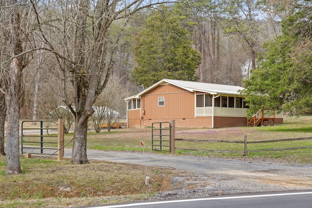 view of front of home with fence, a sunroom, driveway, crawl space, and a front yard