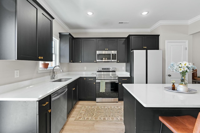 kitchen with light wood-style flooring, stainless steel appliances, a sink, visible vents, and ornamental molding