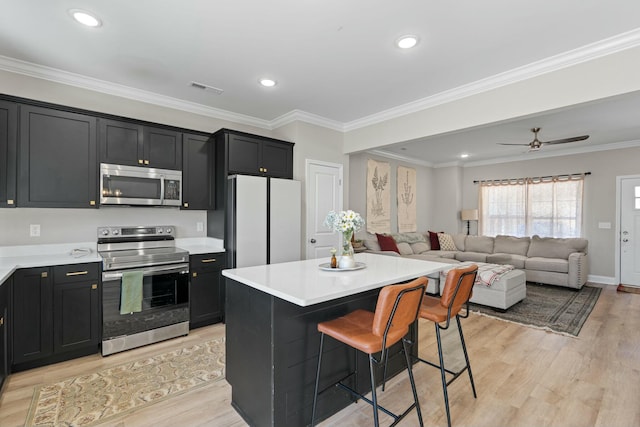 kitchen with a kitchen bar, visible vents, stainless steel appliances, and dark cabinets