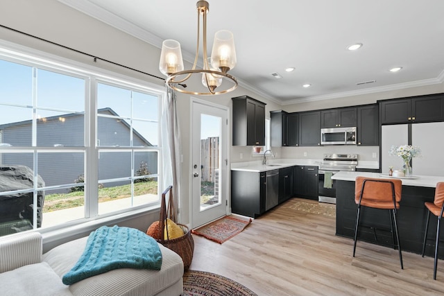 kitchen with appliances with stainless steel finishes, light countertops, a sink, and ornamental molding