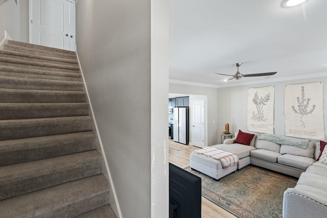 stairway with ornamental molding, wood finished floors, a ceiling fan, and baseboards