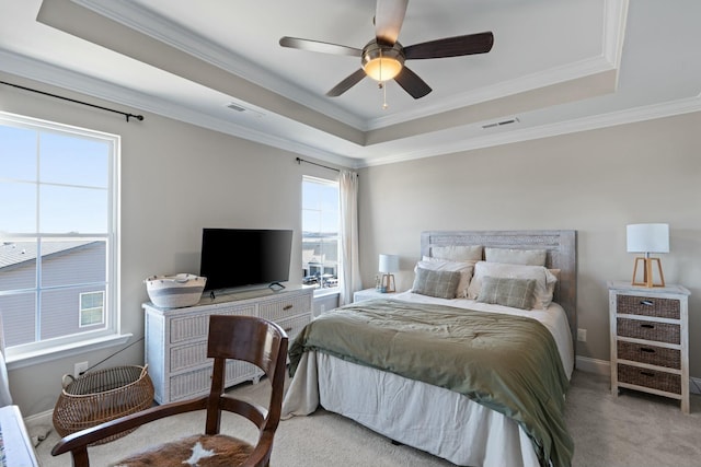 carpeted bedroom with ornamental molding, a tray ceiling, and visible vents