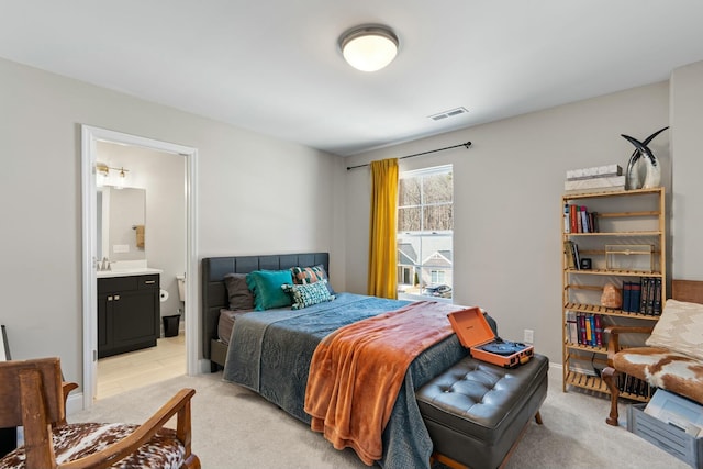 bedroom featuring light colored carpet, visible vents, baseboards, and ensuite bathroom