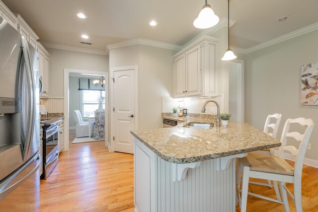 4581 Sweet Berry Ln, Ooltewah, TN 37363 - kitchen featuring stainless steel appliances, ornamental molding, a kitchen bar, a peninsula, and light wood-style flooring