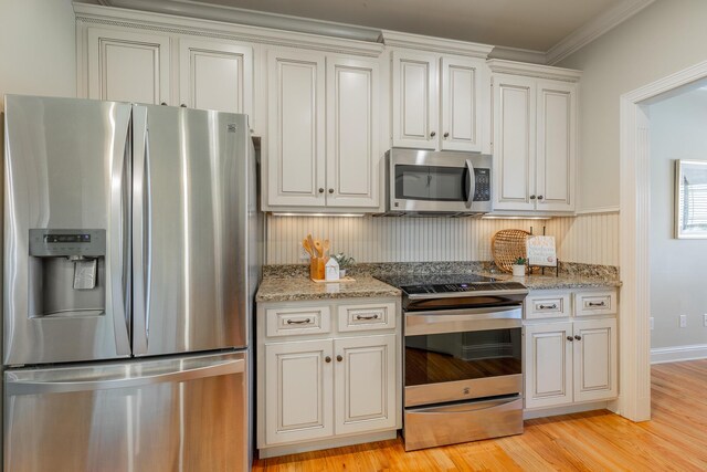 4581 Sweet Berry Ln, Ooltewah, TN 37363 - kitchen featuring appliances with stainless steel finishes, light wood-style floors, light stone countertops, ornamental molding, and white cabinetry