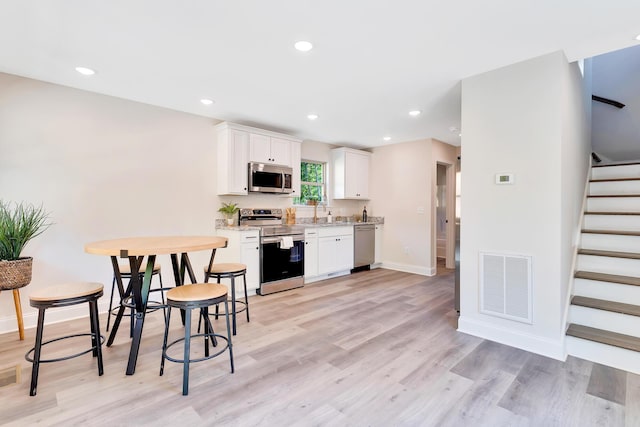 kitchen featuring light wood-style flooring, recessed lighting, visible vents, white cabinets, and appliances with stainless steel finishes