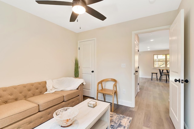 living room with a ceiling fan, baseboards, and wood finished floors