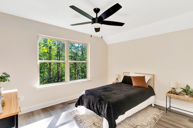 bedroom with a ceiling fan, lofted ceiling, baseboards, and wood finished floors